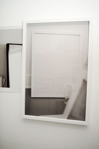 Framed image partially obscured by peeled white paper with a plant shadow crossing the surface